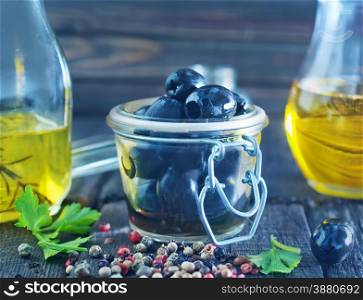 olive oil and black olives on the wooden table