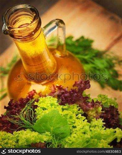 Olive oil and fresh green vegetables on wooden table, tasty salad dressing, lettuce leaves, organic nutrition, healthy eating concept