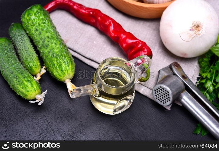 Olive oil and fresh vegetables for salad on a black background, top view