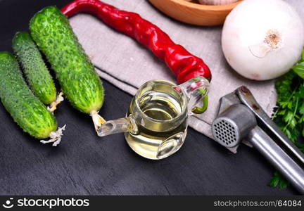 Olive oil and fresh vegetables for salad on a black background, top view