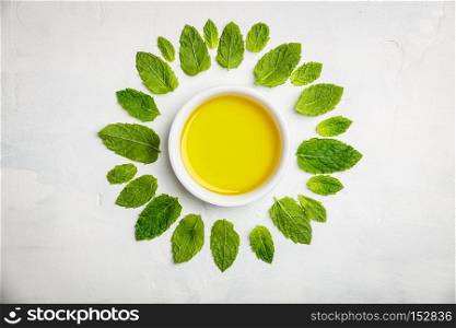 Olive oil and mint leaves on white stone background, flat lay
