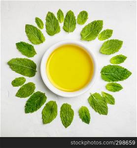 Olive oil and mint leaves on white stone background, flat lay
