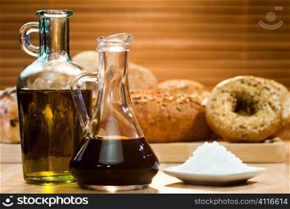 Olive oil, balsamic vinegar, a dish of salt and selection of rustic bread in the background. Shot in golden sunlight
