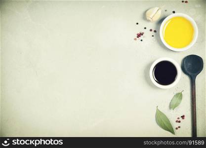 Olive oil, balsamic vinegar, pepper and herbs on concrete background - cooking ingredients -- top view - space for text. Healthy food vegan or diet nutrition concept.