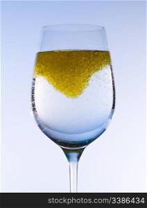 Olive oil being stirred in a large wine goblet forming golden bubbles in the liquid