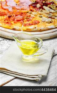 Olive oil for pizza. Gravy boat with olive oil on linen napkin to the pizza