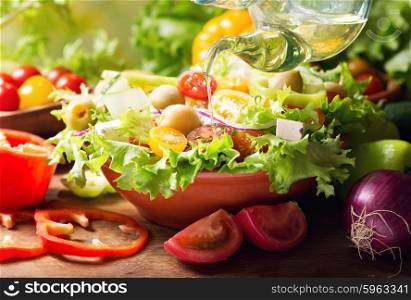 olive oil pouring into bowl of fresh vegetable salad