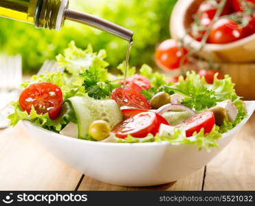 olive oil pouring into bowl of salad