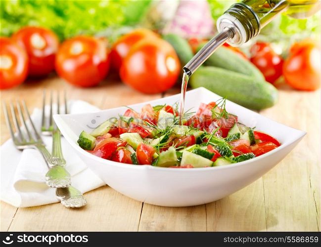 olive oil pouring into bowl of vegetable salad