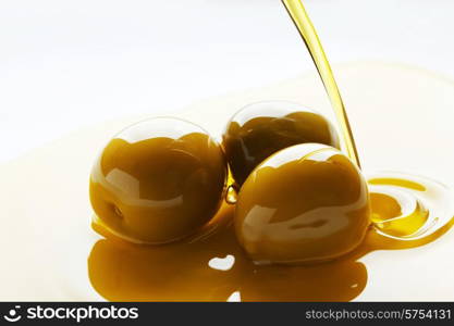 Olive oil pouring on olive fruits on white background. Olive oil pouring