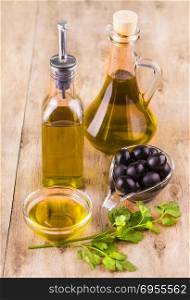 Olive oil with fresh herbs and Black olives on wooden background