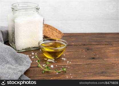 Olive oil with thyme and salt flower on wooden background.