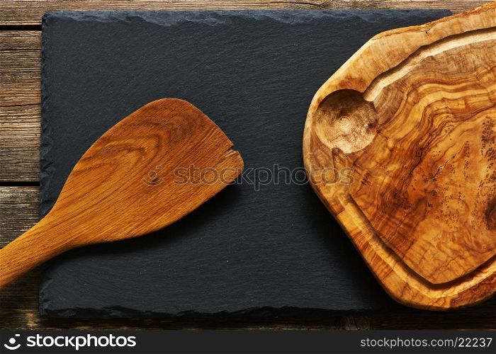 Olive wood cutting board and spatula over slate