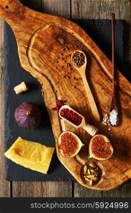 Olive wood cutting board with spices and fig over slate
