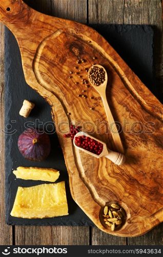 Olive wood cutting board with spices and fig over slate