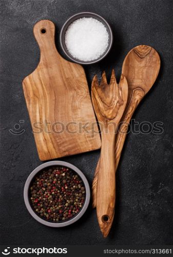 Olive wood kitchen utensils with chopping board on stone table background. Top view.