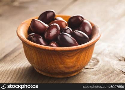 Olives calamata in wooden bowl on the table. The olives calamata