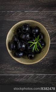 Olives in a ceramic bowl on a wooden table.