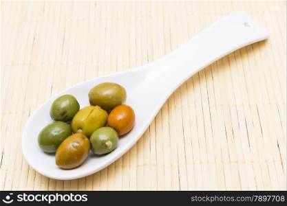 olives in a spoon on a wooden background