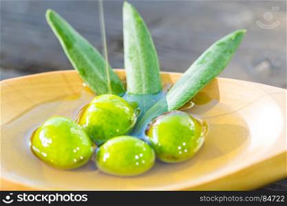 Olives in a spoon over extra virgin olive oil