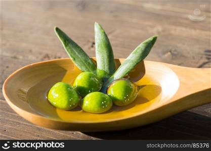 Olives in a spoon over extra virgin olive oil