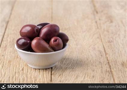 olives into in a bowl on wooden table background