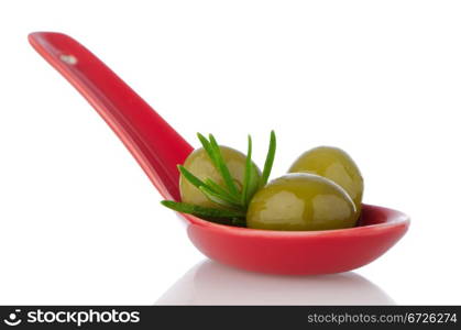 Olives on ceramic spoon with basil and olive oil