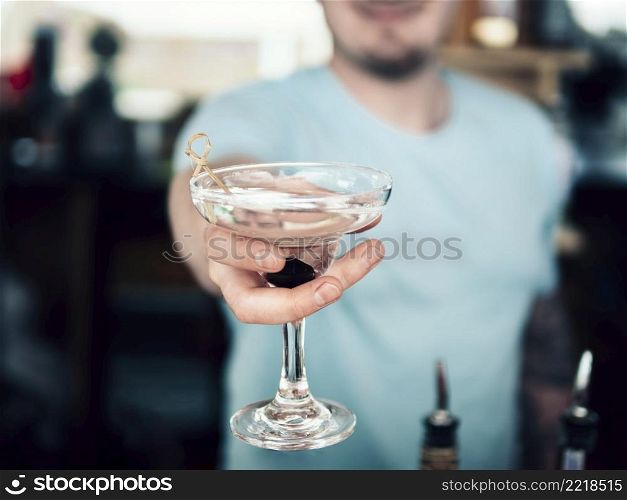 OLYMPUS DIGITAL CAMERA. anonymous barman serving decorated glass beverage