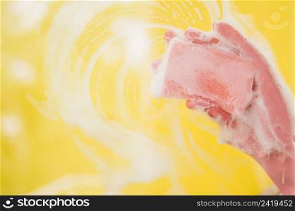 OLYMPUS DIGITAL CAMERA. close up hand wearing pink gloves washing yellow backdrop with sponge