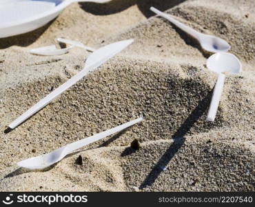OLYMPUS DIGITAL CAMERA. close up plastic cutlery sand beach