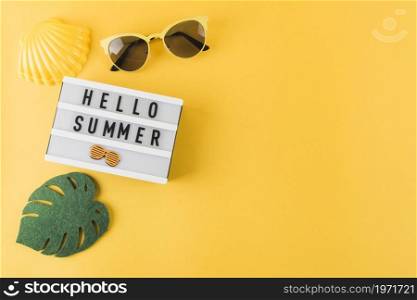 OLYMPUS DIGITAL CAMERA. High resolution photo. overhead view scallop sunglass leaf hello summer light box yellow backdrop. High quality photo