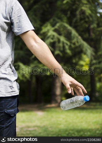 OLYMPUS DIGITAL CAMERA. man hand throwing plastic water bottle park