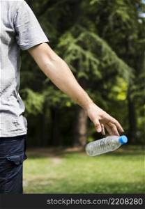 OLYMPUS DIGITAL CAMERA. man hand throwing plastic water bottle park