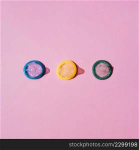 OLYMPUS DIGITAL CAMERA. top view coloured condoms pink background