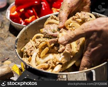 OLYMPUS DIGITAL CAMERA. unrecognizable cook mixing pieces meat onion shashlik
