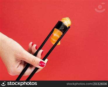 OLYMPUS DIGITAL CAMERA. woman holding chop sticks salmon sushi red background