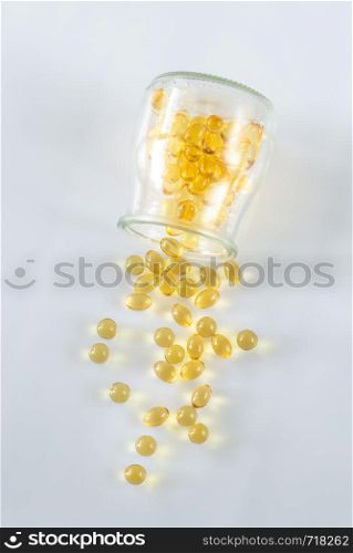 Omega-3 fish oil capsules pouring out from the glass jar on the white background