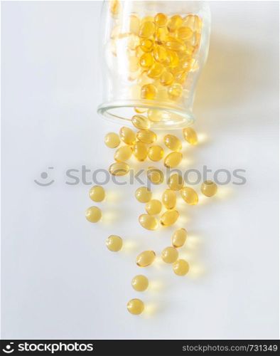 Omega-3 fish oil capsules pouring out from the glass jar on the white background