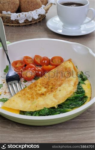 Omelet with spinach and roasted tomatoes in a pan