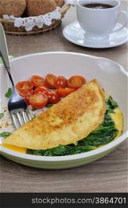 Omelet with spinach and roasted tomatoes in a pan