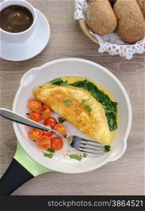 Omelet with spinach, cheese and roasted tomatoes in a pan