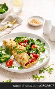 Omelette stuffed with tomato, broccoli feta cheese and fresh green salad. Healthy diet food for breakfast
