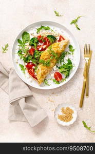 Omelette stuffed with tomato, broccoli feta cheese and fresh green salad. Healthy diet food for breakfast. Top view