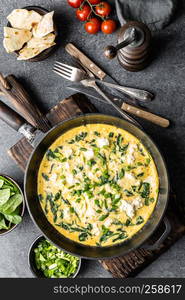 omelette with spinach and cheese in a pan on the concrete background top view