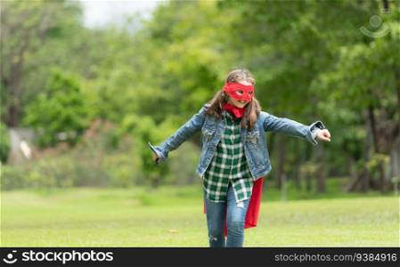 On a beautiful day in the park, a young girl enjoys her vacation. Playful with a red superhero costume and mask.