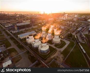 On a big site plant located distillation systems, oil reservoirs, coolers etc. Large cooling pipes from which steam is flowing at an oil refinery. Aerial view