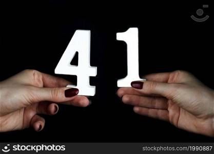 On a black background, female hand with number forty-one.. On the female palms figure forty-one.
