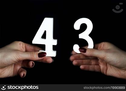On a black background, female hand with number forty-three.. On the female palms figure forty-three.