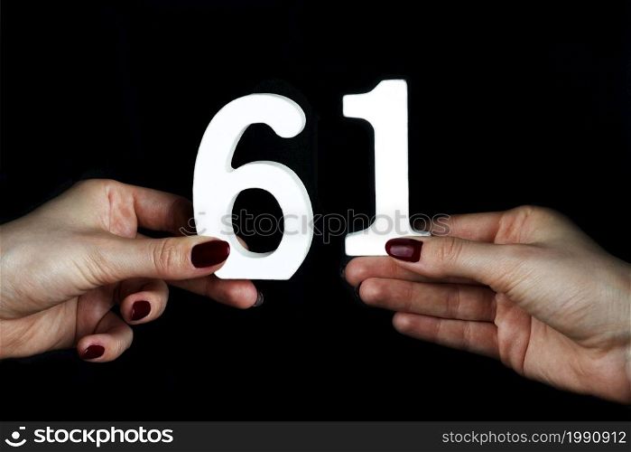 On a black background, female hand with number nine.. To female hands the number nine.