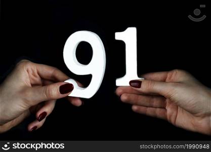 On a black background, female hand with numbers ninety-one.. To female hands the figure of ninety-one.